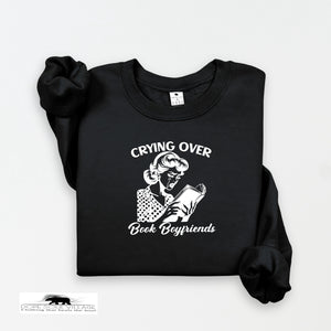 Black sweatshirt with graphic and text 'Crying Over Book Boyfriends' on a white background