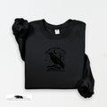 Black sweatshirt with a crow design and text on a white background