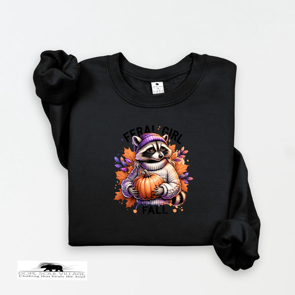 Black sweatshirt with a raccoon holding a pumpkin and 'Feral Girl Fall' text on a white background.