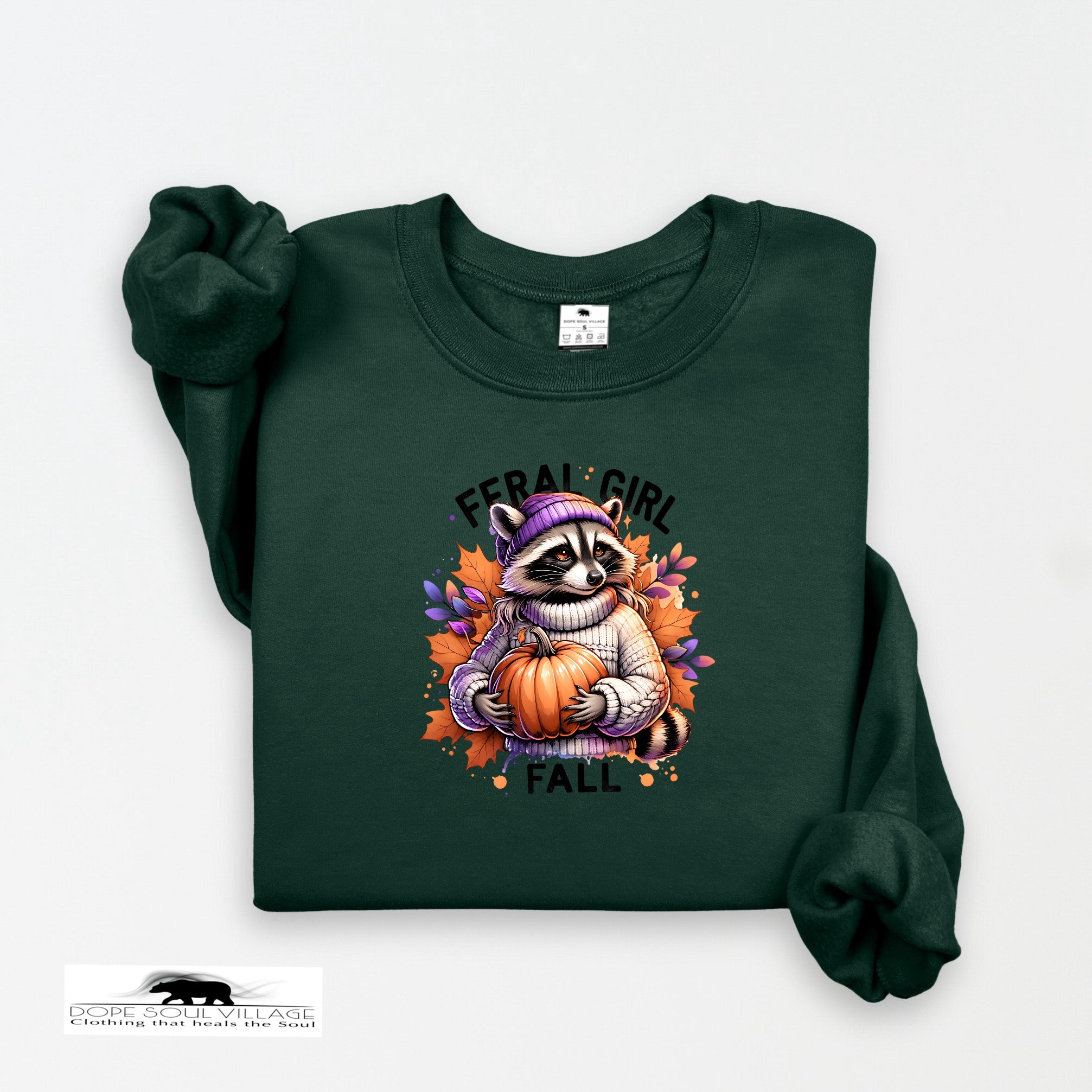 Green sweatshirt with a raccoon holding a pumpkin and 'Feral Girl Fall' text on a white background.