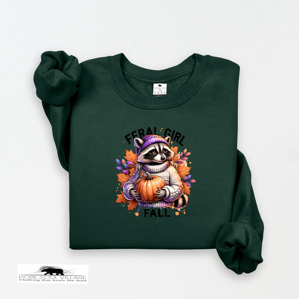 Green sweatshirt with a raccoon holding a pumpkin and 'Feral Girl Fall' text on a white background.
