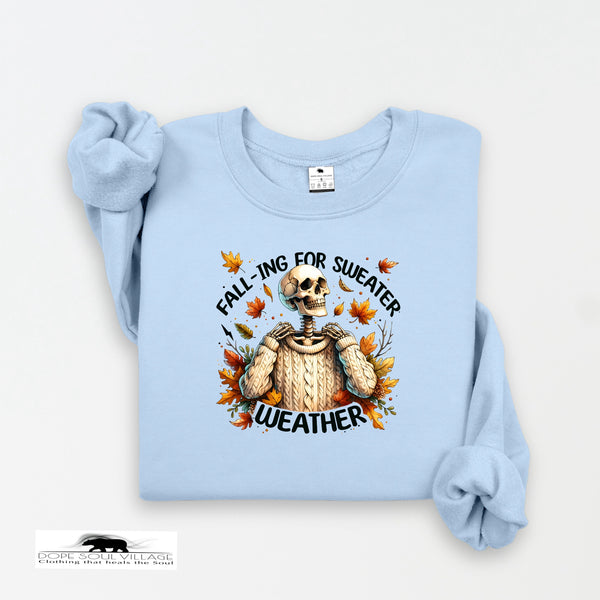 Light blue sweatshirt with skeleton wearing a sweater and autumn leaves design on a white background.