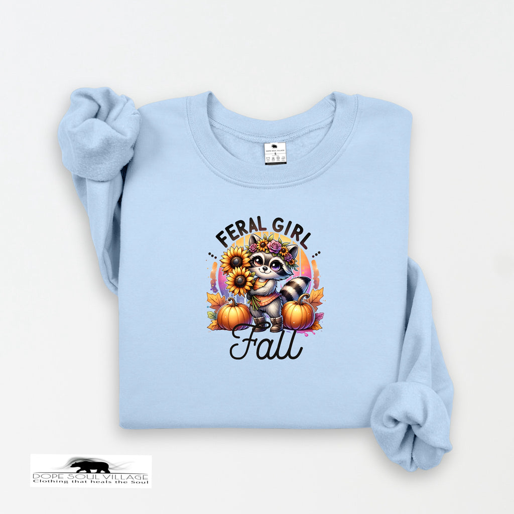 Light blue sweatshirt with a raccoon graphic and 'Feral Girl Fall' text on a white background