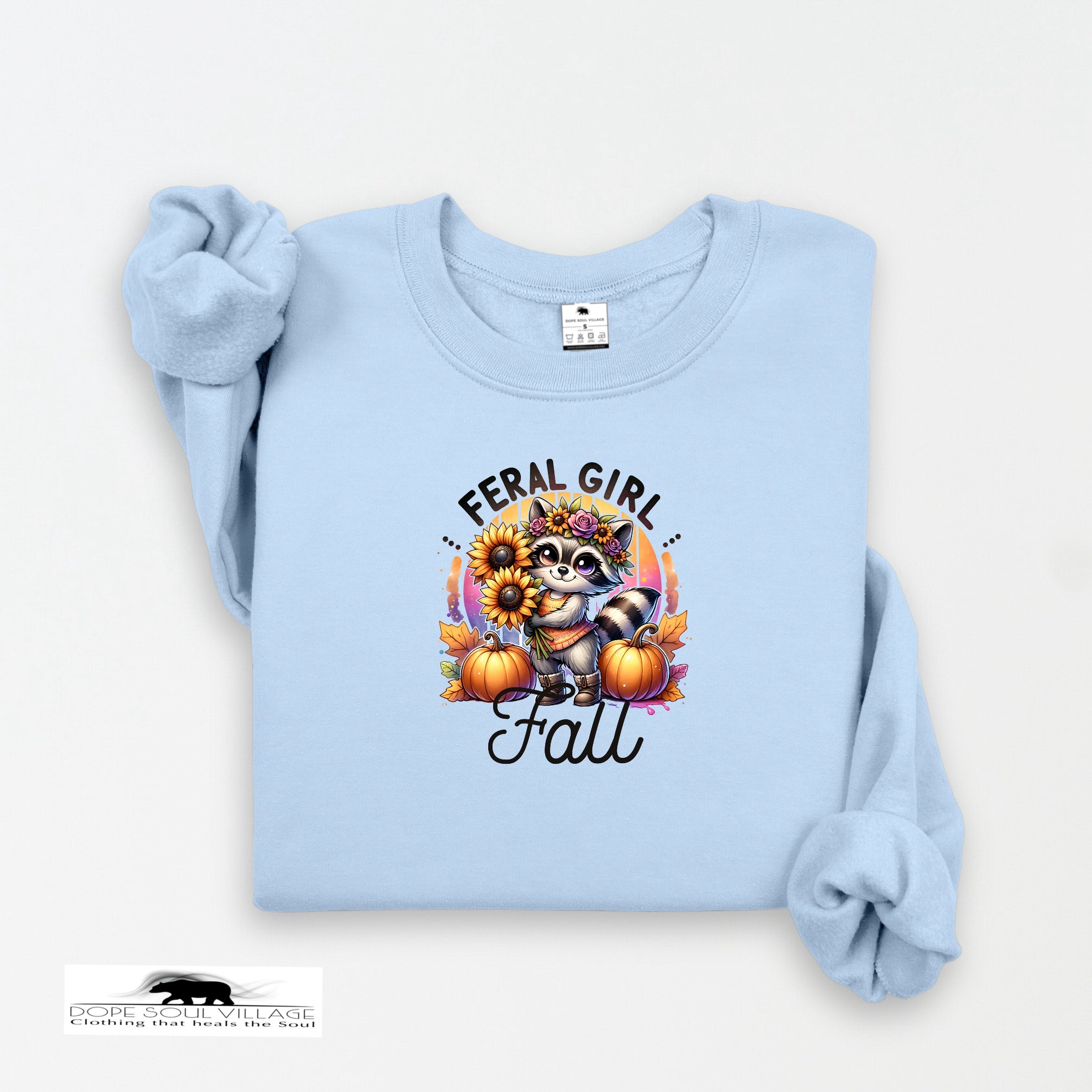 Light blue sweatshirt with a raccoon graphic and 'Feral Girl Fall' text on a white background