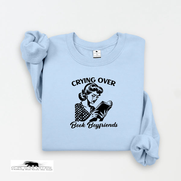 Light blue sweatshirt with graphic and text 'Crying over Book Boyfriends' on a white background