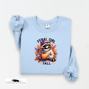 Light blue sweatshirt with a raccoon holding a pumpkin and 'Feral Girl Fall' text on a white background.