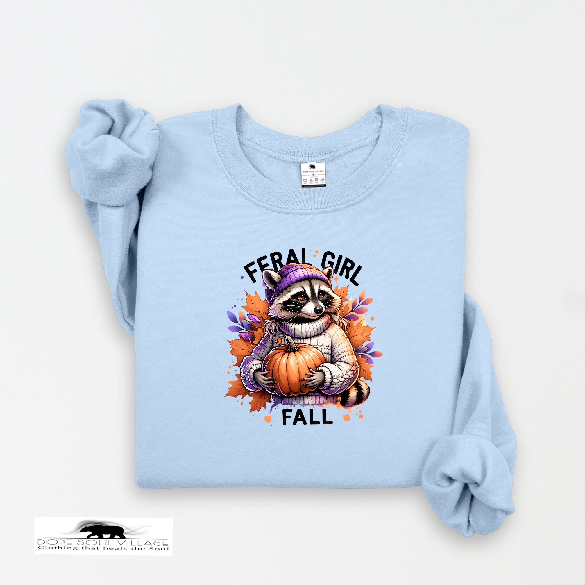 Light blue sweatshirt with a raccoon holding a pumpkin and 'Feral Girl Fall' text on a white background.