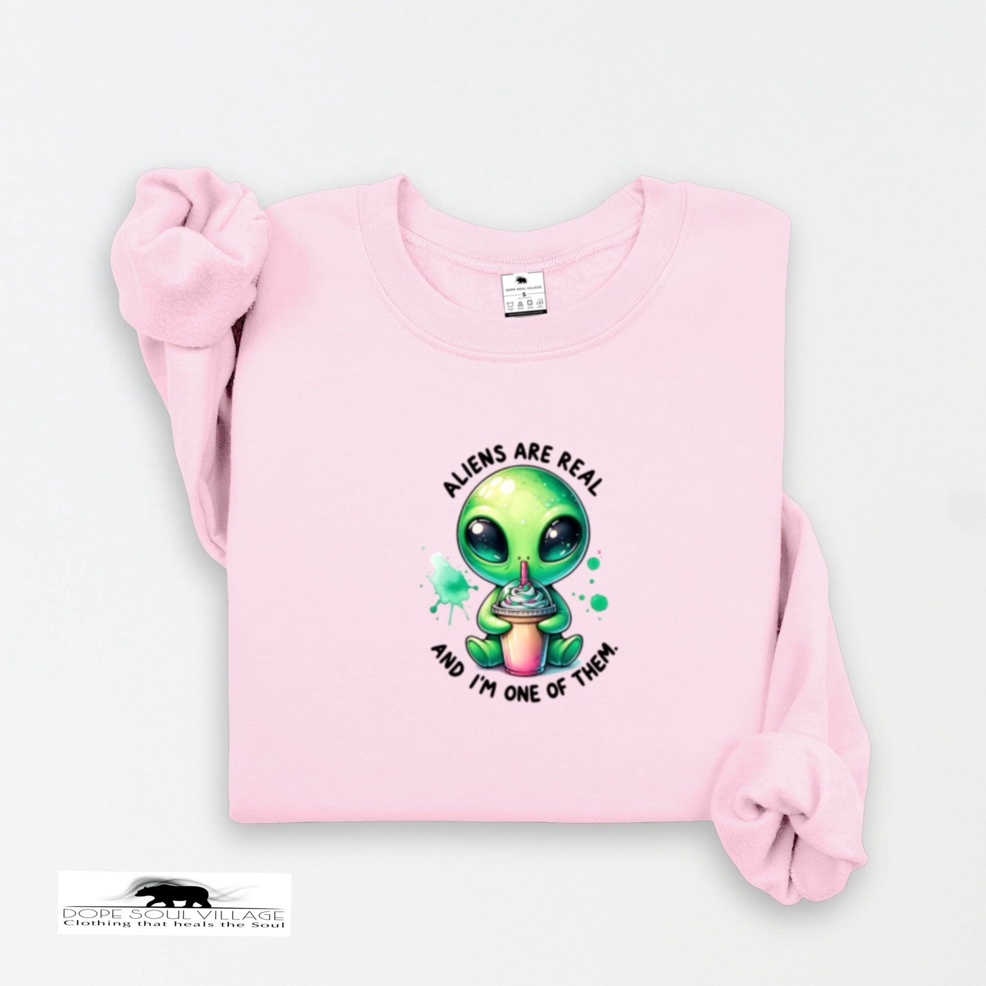 Pink sweatshirt with a green alien graphic and text on a white background