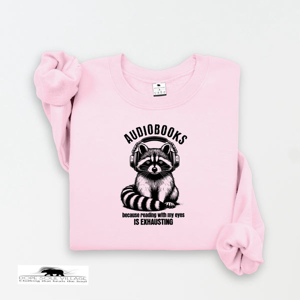 Pink sweatshirt with raccoon graphic and text on a light gray background