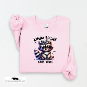 Pink sweatshirt with a raccoon graphic and text on a white background