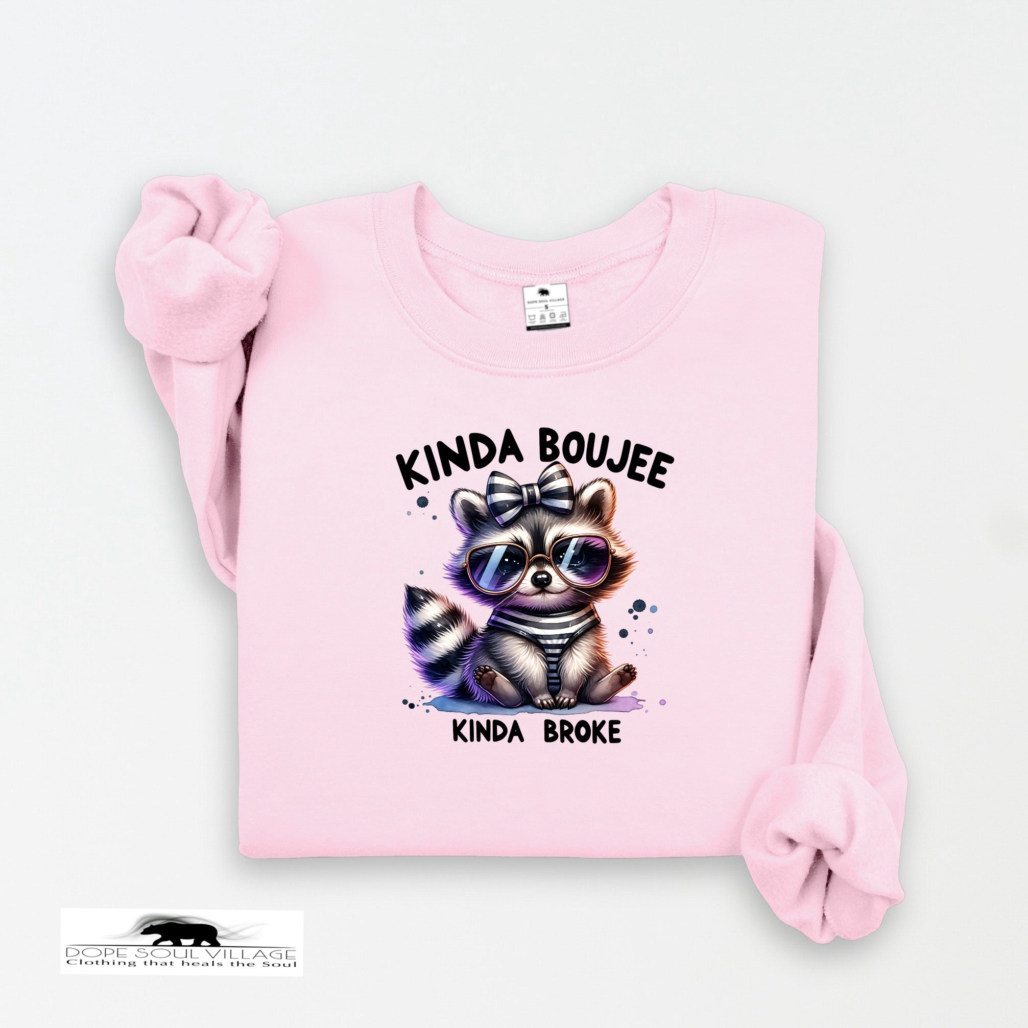 Pink sweatshirt with a raccoon graphic and text on a white background