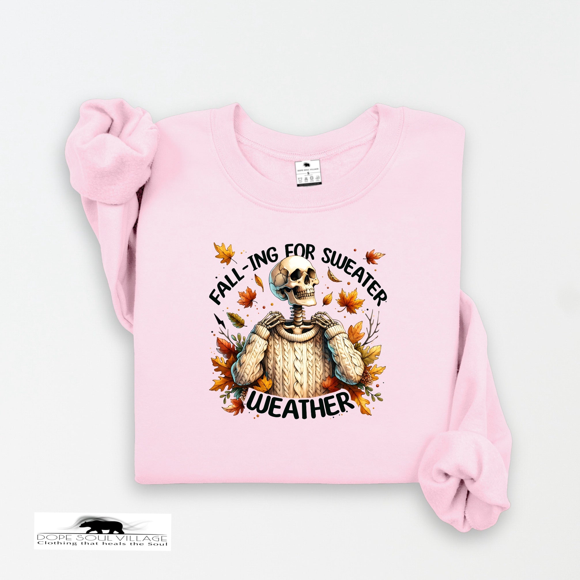 Pink sweatshirt with skeleton wearing a sweater graphic and text 'Falling for Sweater Weather' on a white background.