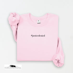Pink sweatshirt with '#justicedenied' text on a light gray background rebecca goodwin