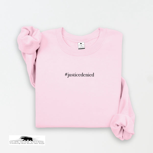 Pink sweatshirt with '#justicedenied' text on a light gray background rebecca goodwin