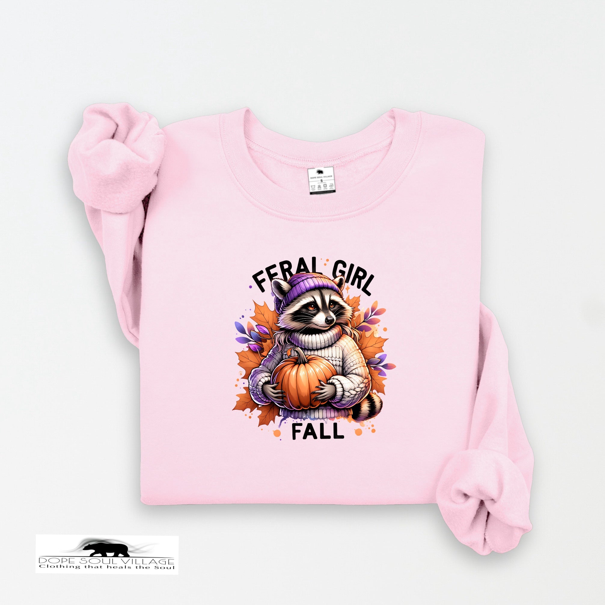 Pink sweatshirt with a raccoon holding a pumpkin and 'Feral Girl Fall' text on a white background