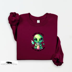 Maroon sweatshirt with a green alien graphic and text on a white background