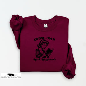 Maroon sweatshirt with graphic and text 'Crying Over Book Boyfriends' on a white background