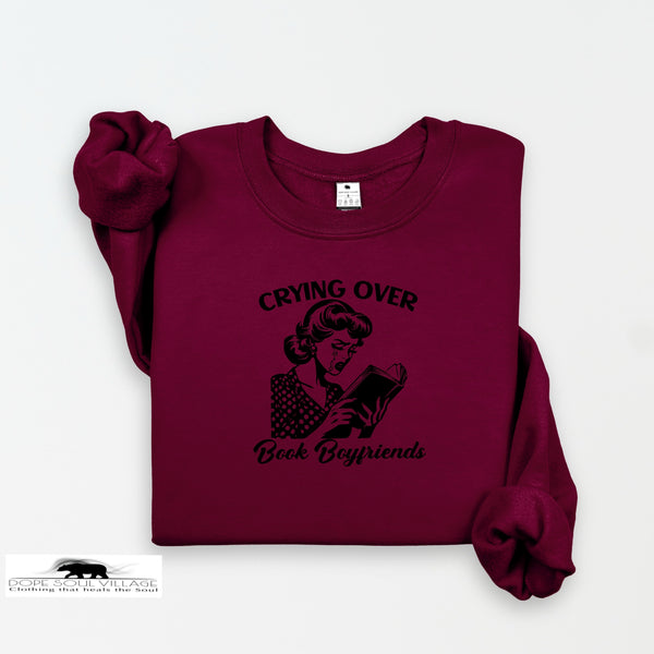 Maroon sweatshirt with graphic and text 'Crying Over Book Boyfriends' on a white background