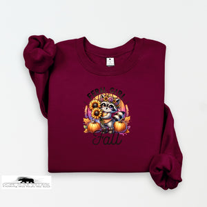 Maroon sweatshirt with a raccoon and fall-themed design on a white background