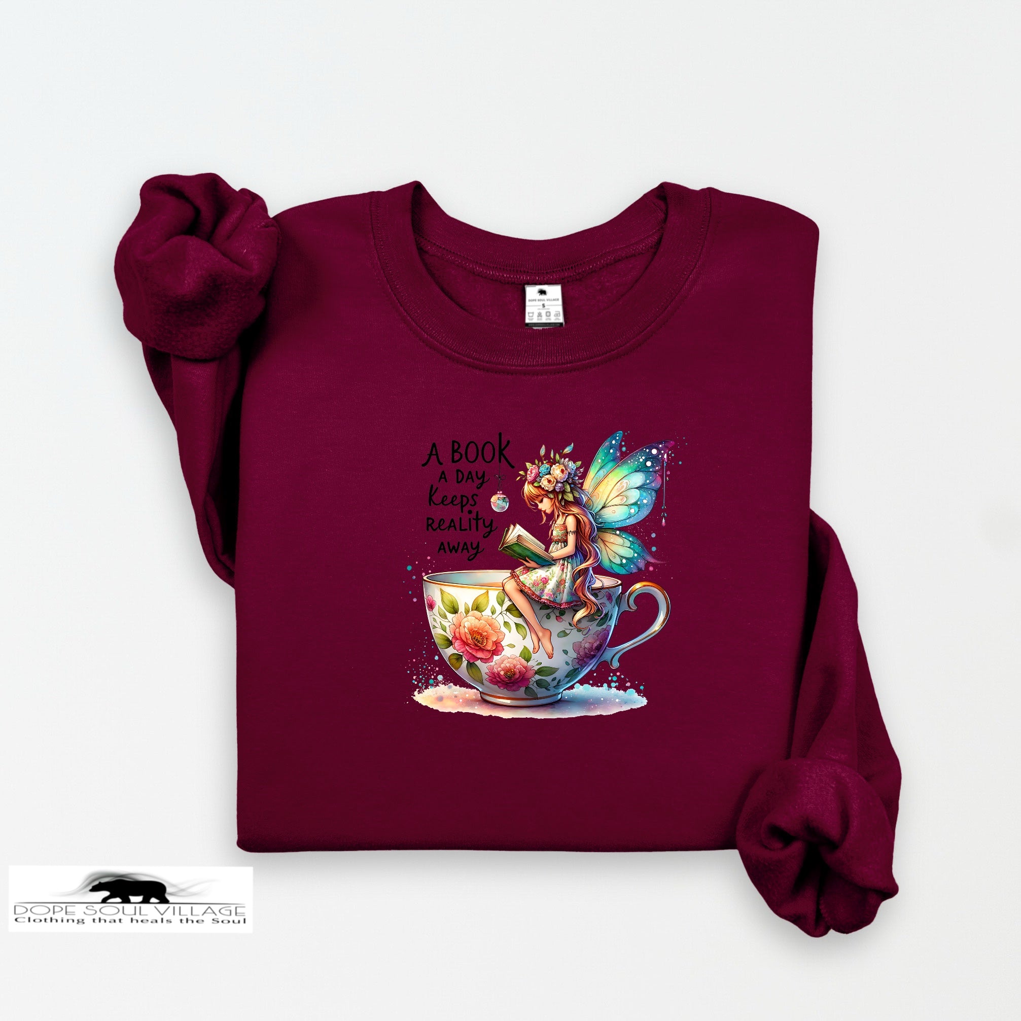 Maroon sweatshirt with fairy and book design on a white background