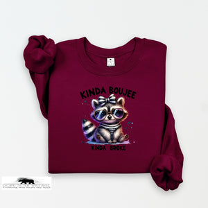 Maroon sweatshirt with a raccoon graphic and text on a white background