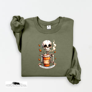 Green sweatshirt with a skeleton design holding a pumpkin and text on a white background