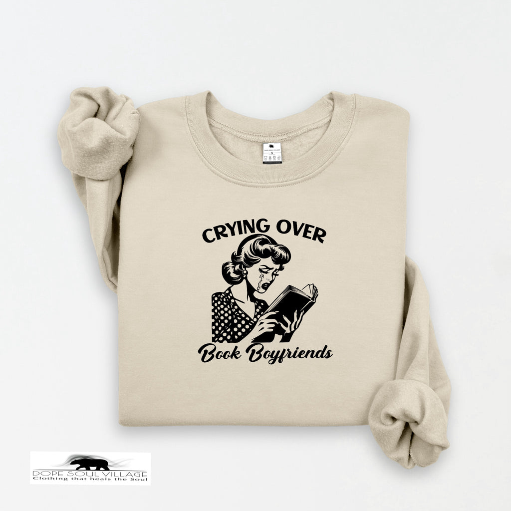 Beige sweatshirt with graphic and text 'Crying Over Book Boyfriends' on a white background