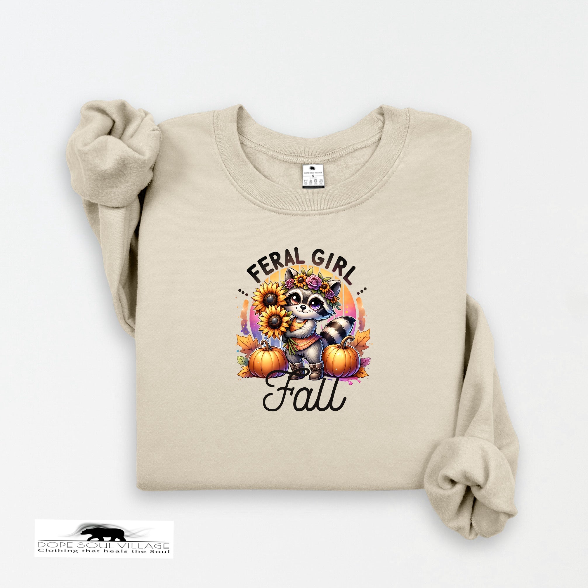 Beige sweatshirt with a raccoon graphic and 'Feral Girl Love Fall' text on a white background