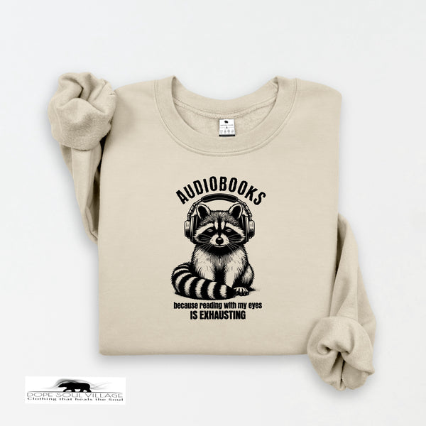 Beige sweatshirt with a raccoon graphic and 'audiobooks' text on a white background