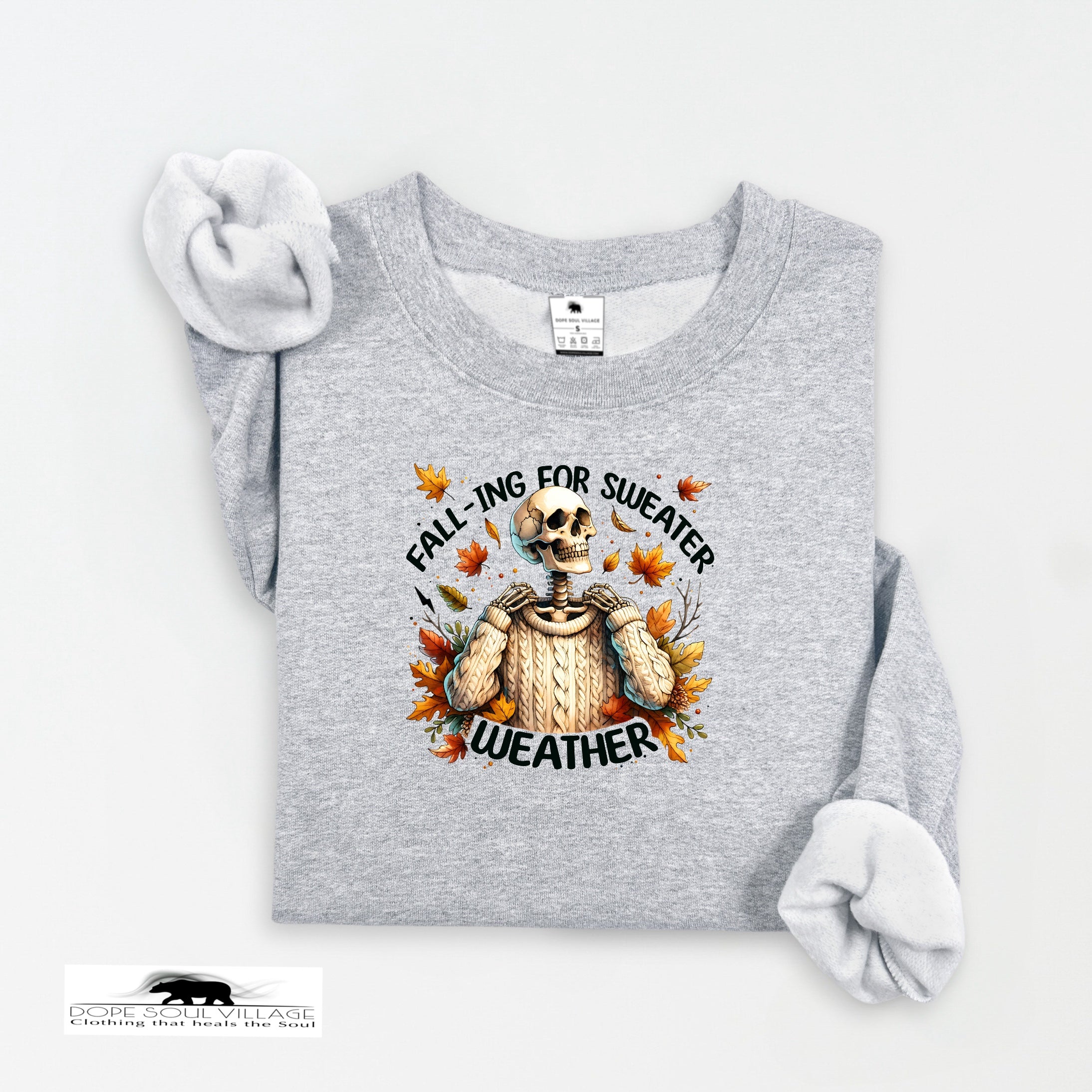 Gray sweatshirt with skeleton and 'fall-ing for sweater weather' text on a white background