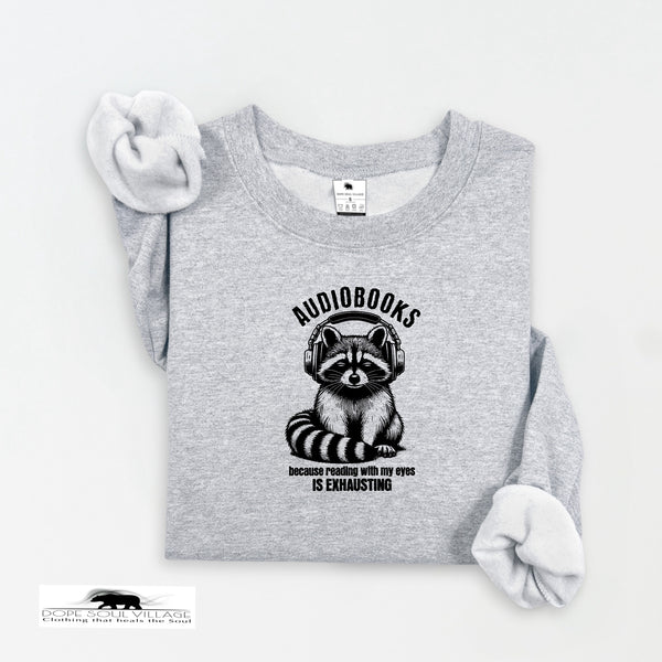 Gray sweatshirt with a raccoon wearing headphones and text 'AUDIODESks because reading with my eyes is exhausting' on a white background.