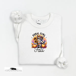 White t-shirt with a graphic design featuring a raccoon, pumpkins, and text on a white background.