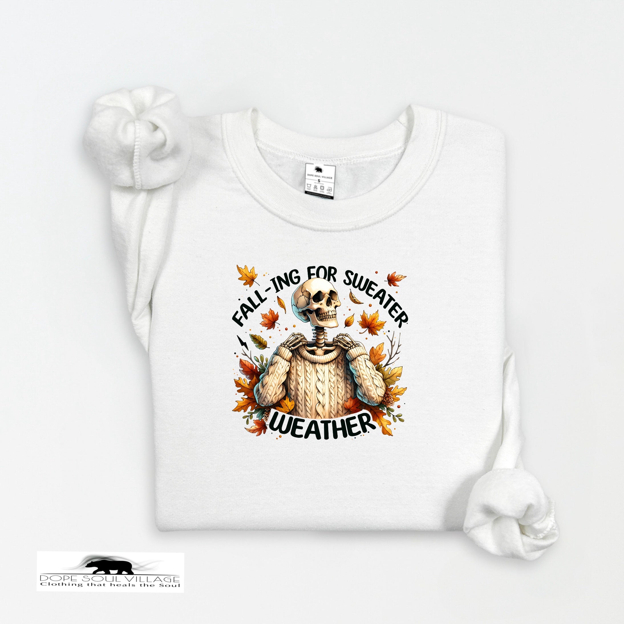White sweatshirt with a skeleton wearing a sweater and autumn leaves design on a white background.