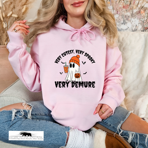 Person wearing a pink hoodie with a ghost and text design, sitting on a couch dope soul village