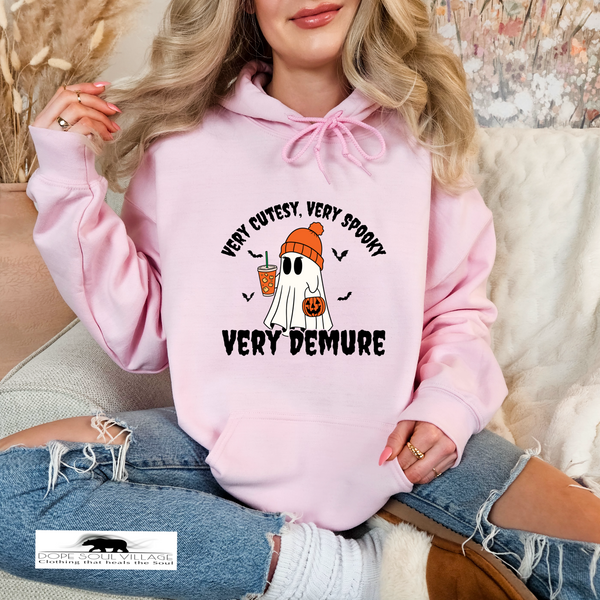 Person wearing a pink hoodie with a ghost and text design, sitting on a couch dope soul village