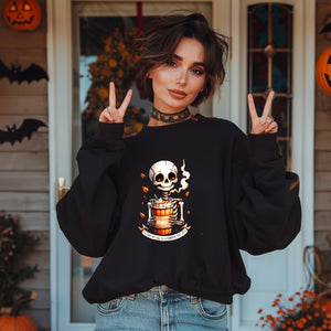 Woman wearing a black sweatshirt with a skull design, making peace signs in front of Halloween decorations.