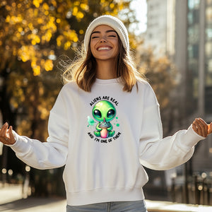 Woman wearing a white sweatshirt with an alien graphic and text, standing outdoors.Dope SOul Village
