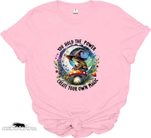 Pink t-shirt with a witch and mushroom design and motivational text on a white background