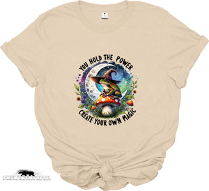Beige t-shirt with a witch and mushroom design and motivational text on a white background