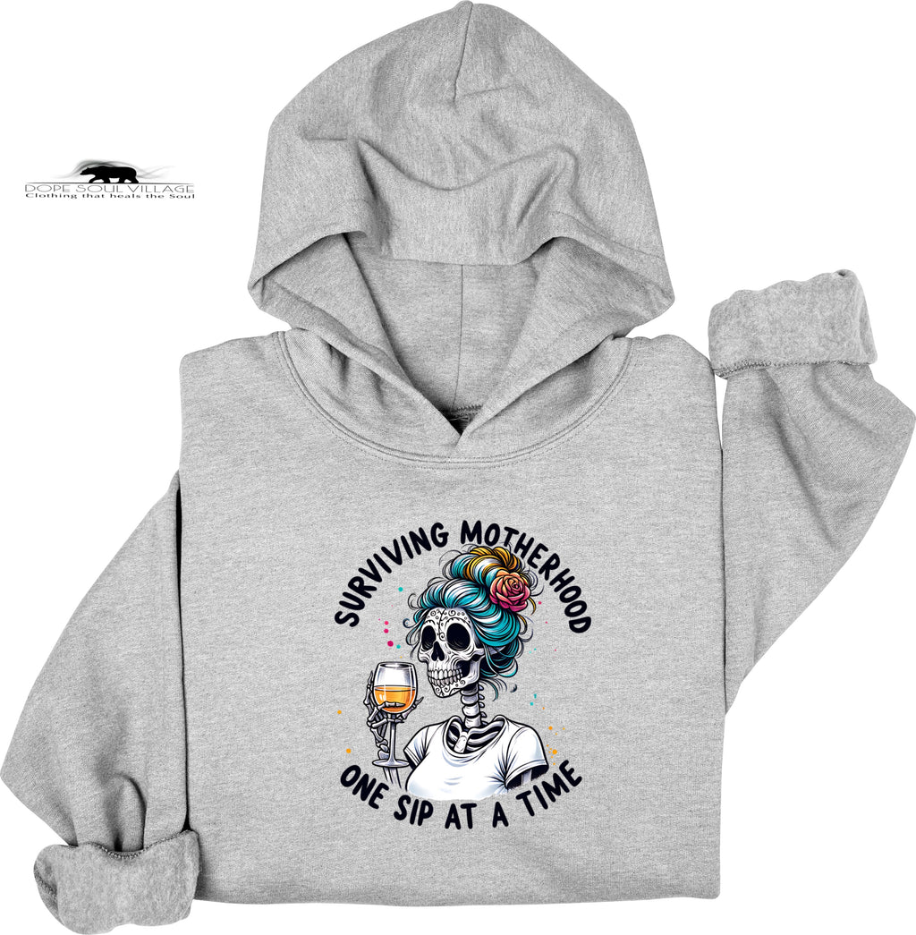Gray hoodie with a skeleton design and text 'Surviving Motherhood One Sip at a Time' on a white background
