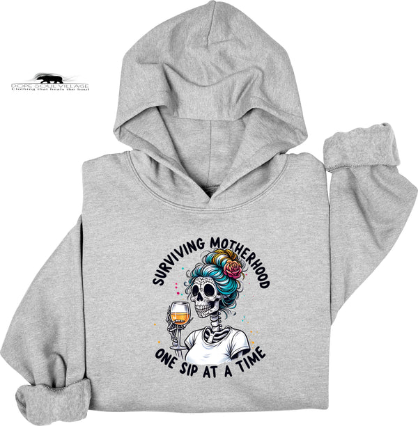 Gray hoodie with a skeleton design and text 'Surviving Motherhood One Sip at a Time' on a white background
