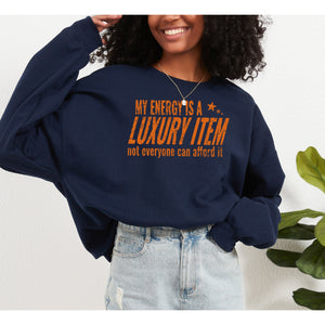 Person wearing a navy blue sweatshirt with orange text, standing against a white background with a plant.