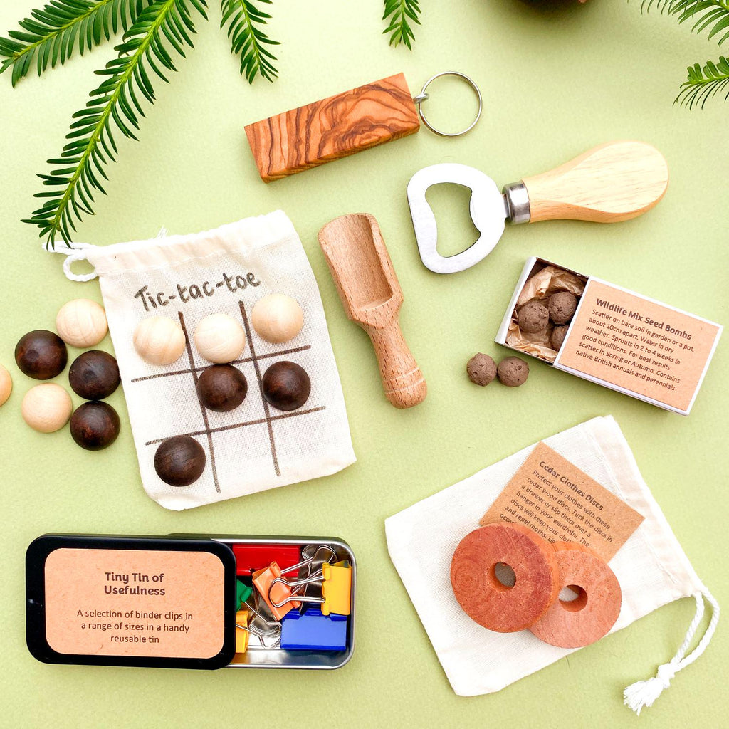 Mini gifts from our cracker gifts selection including wooden bottle opener, olive wood keyring, seedballs, red cedar clothes protector disks, small wooden scoop, and a handy tin of paper clips