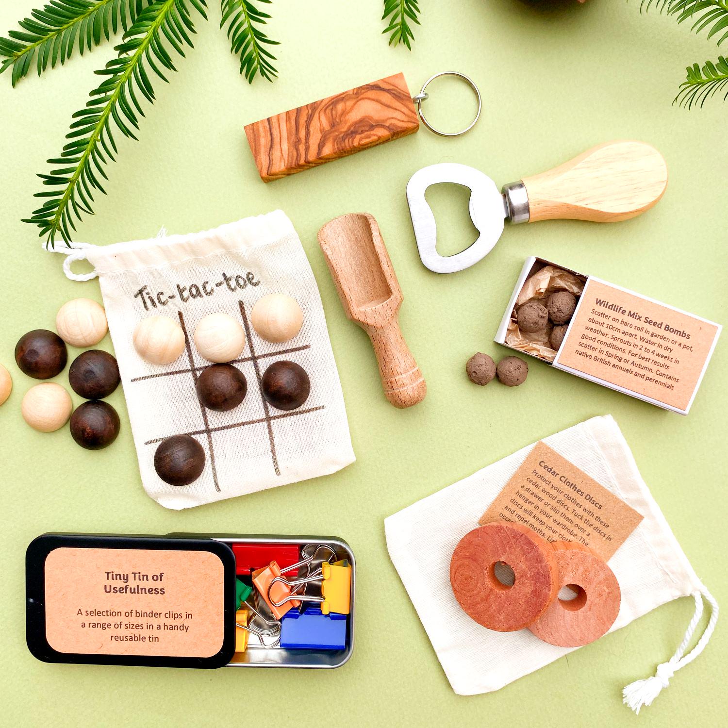 Mini gifts from our cracker gifts selection including wooden bottle opener, olive wood keyring, seedballs, red cedar clothes protector disks, small wooden scoop, and a handy tin of paper clips