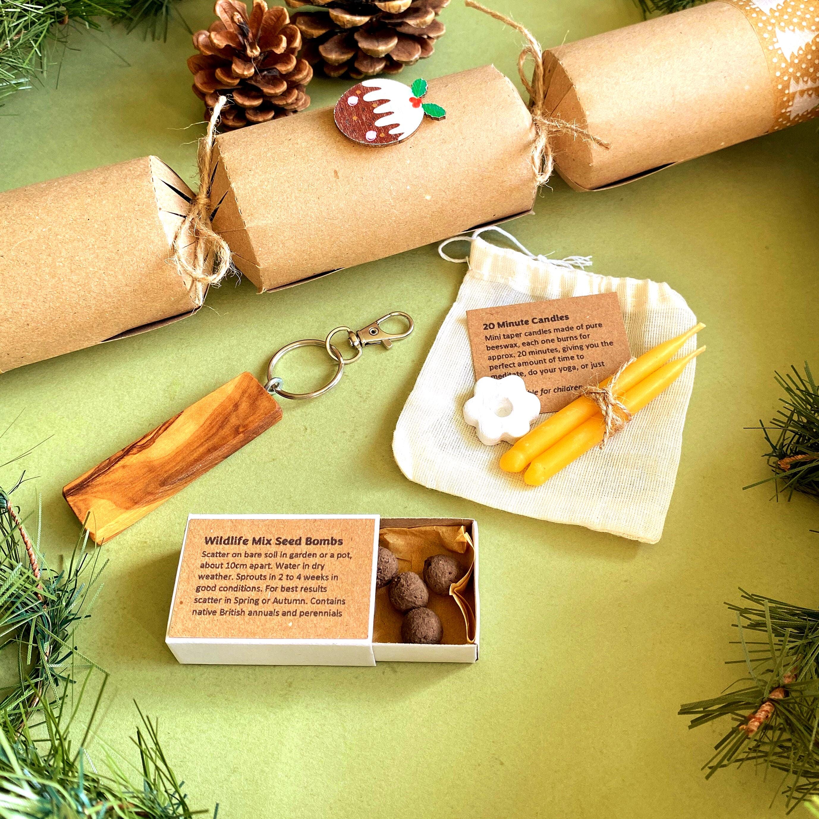 Close up of the wildlife mix seedballs, olive wood keyring and pair of mini beeswax candles, with an eco-friendly Christmas cracker in the background