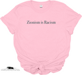 A light pink short-sleeve t-shirt with the text 'Zionism is Racism' printed in black serif font across the chest. The t-shirt is styled with a knot at the bottom hem, set against a plain white background. Available from Dope Soul Village women's marketplace.
